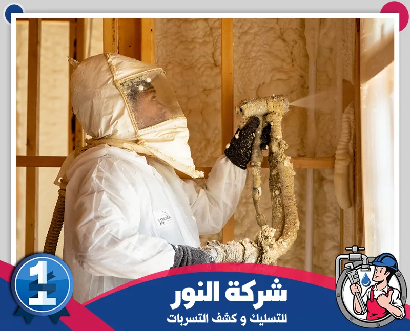شركة عزل فوم بالقصيم | 0546824999 | شركة النور رجل يرتدي بدلة بيضاء يرش رغوة عازلة على جدار، يمثل شركة عزل رغوي في القصيم.