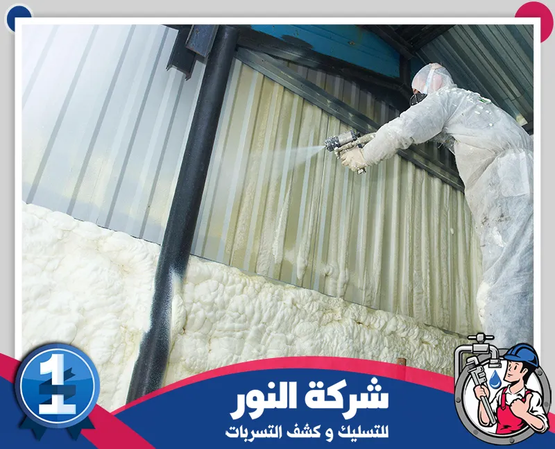 شركة عزل اسطح بالطائف | 0546824999 | شركة النور رجل يرتدي ملابس واقية بيضاء يضع عازلاً رغوياً على جدار، لعرض أعمال العزل السطحي في الطائف.