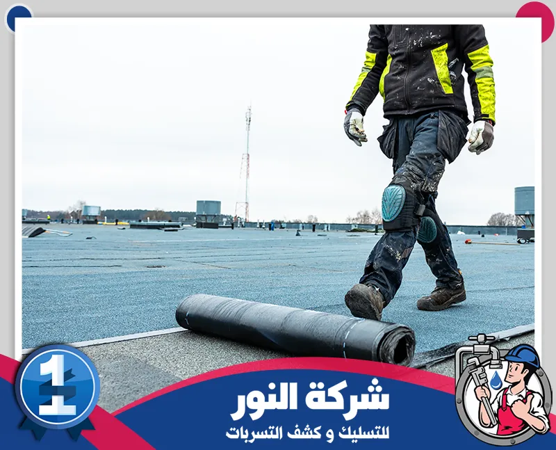 ارخص شركة عزل اسطح بجدة | 0546824999 | شركة النور رجل يمشي على سطح مبنى، ويقوم بفرد مادة العزل على السطح، لعرض أعمال عزل الأسطح في جدة.