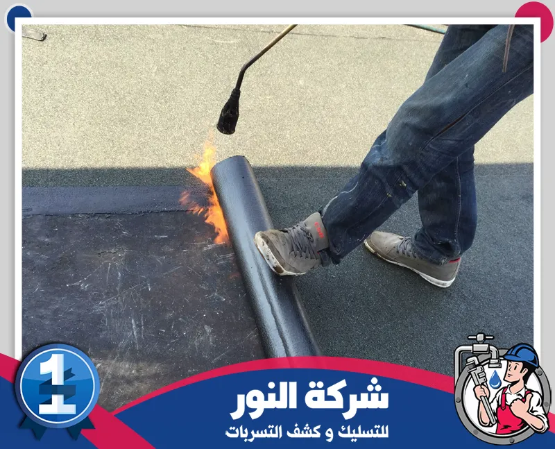 عزل الأسطح بمادة الصوف الصخري بعرعر 0546824999 شركة النور للتسليك عامل يقوم بتركيب عزل أسطح حراري ومائي باستخدام لفائف العزل لحماية المبنى.