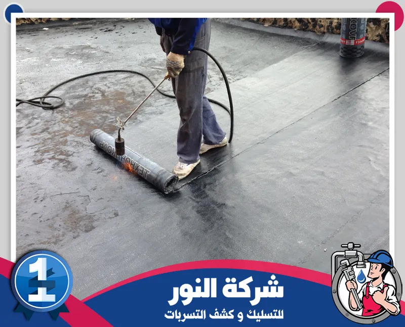 افضل شركة عزل اسطح | شركة النور للتسليك عامل يستخدم أداة رش لتوزيع مادة العزل على سطح المبنى بشكل متساوٍ، ضمن مراحل تنفيذ شركة عزل اسطح بالنعيرية لحماية الأسطح من تسرب المياه والرطوبة.