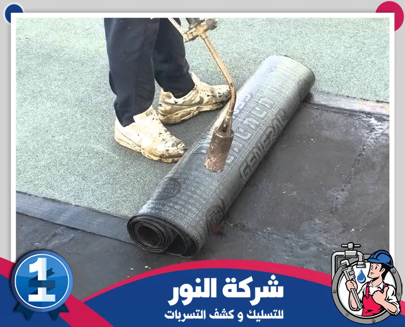 مواد عزل الاسطح | شركة النور للتسليك فني يقوم بدهان طبقة عزل على سطح المبنى باستخدام أسطوانة توزيع لضمان تغطية متساوية، ضمن أعمال شركة عزل اسطح بالنعيرية لحماية الأسطح من الرطوبة وتسربات المياه.