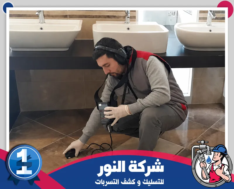 فني يستخدم جهاز كشف صوتي وسماعات لفحص أرضية حمام أسفل المغاسل ضمن خدمات شركة كشف تسربات المياه بعرعر