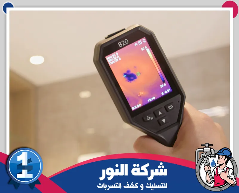 يد تمسك كاميرا حرارية تظهر على شاشتها بقعة زرقاء في ألوان برتقالية مع شعار النور للتسليك أسفل الصورة